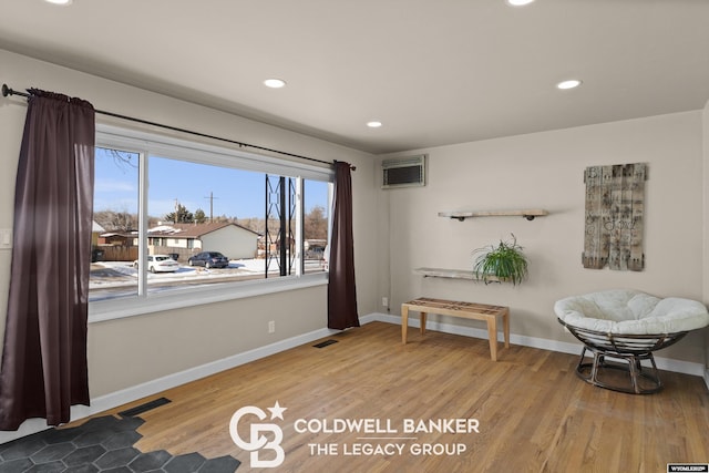 sitting room featuring light hardwood / wood-style floors and an AC wall unit