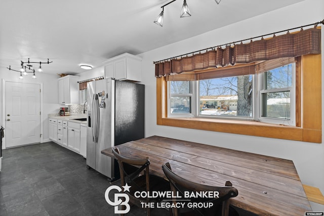 kitchen featuring stainless steel fridge, white cabinetry, and sink