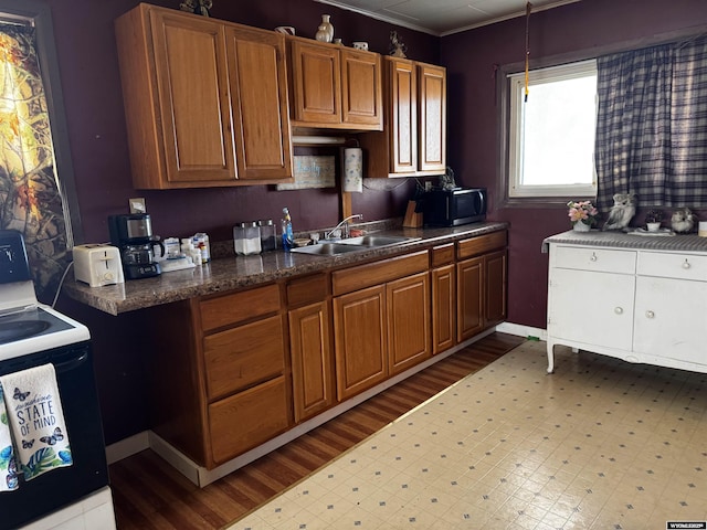 kitchen with white range with electric cooktop, light hardwood / wood-style floors, sink, and pendant lighting