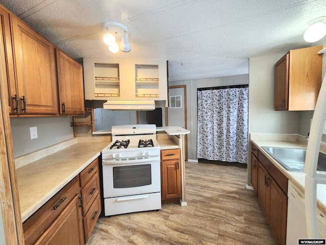 kitchen featuring white appliances, sink, exhaust hood, and light hardwood / wood-style flooring