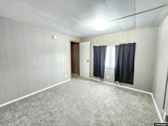 carpeted spare room featuring wood walls