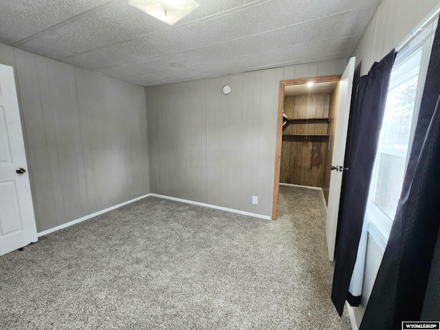 unfurnished bedroom with carpet flooring and wood walls