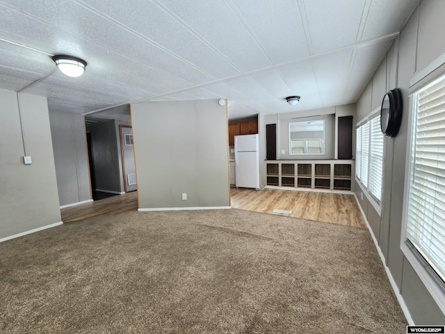 unfurnished living room featuring a textured ceiling and light carpet