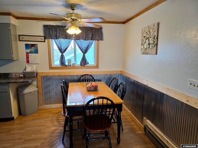 dining room featuring ceiling fan, wood-type flooring, ornamental molding, and a textured ceiling