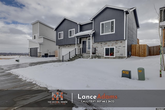 view of front of property featuring a garage, stone siding, and fence