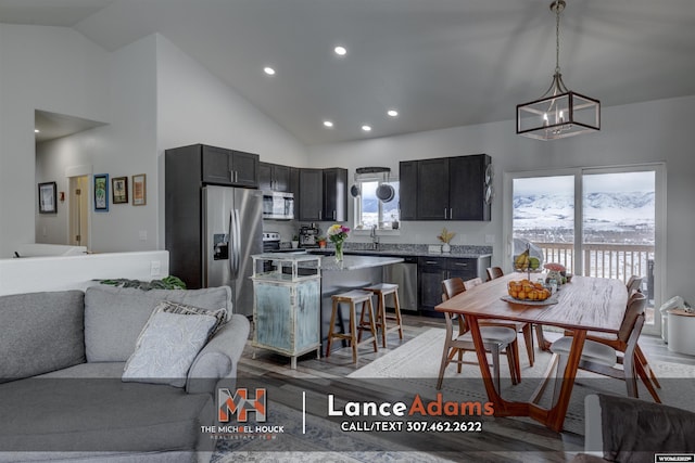 kitchen featuring a sink, a kitchen island, open floor plan, appliances with stainless steel finishes, and light wood finished floors