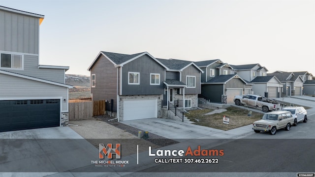 view of front of house with a garage, fence, driveway, stone siding, and a residential view