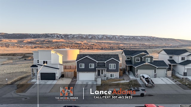 view of front of house with a garage, a residential view, a mountain view, and driveway