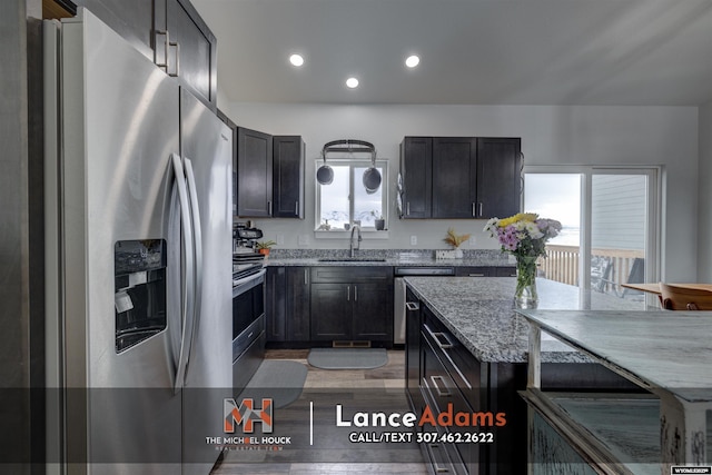 kitchen with light stone counters, recessed lighting, a sink, light wood-style floors, and appliances with stainless steel finishes