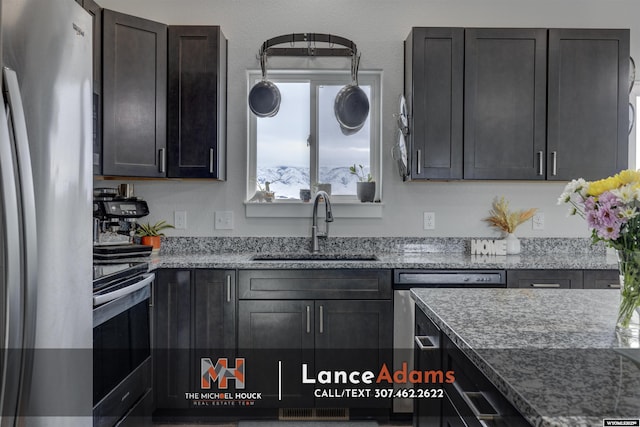 kitchen with light stone countertops, appliances with stainless steel finishes, and a sink