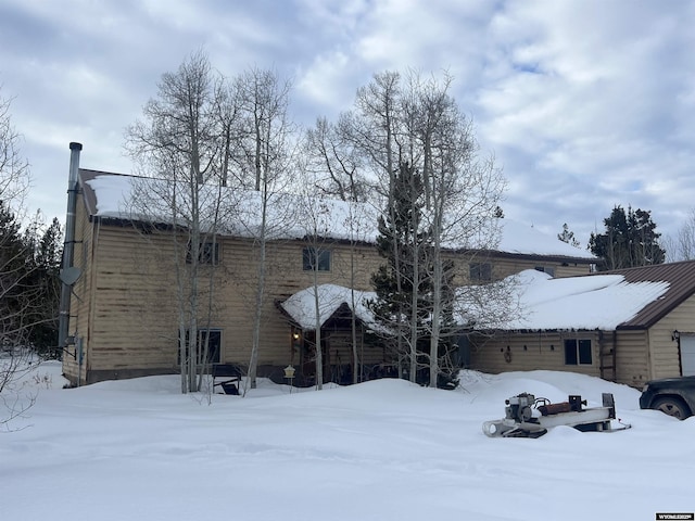 snow covered rear of property with a garage