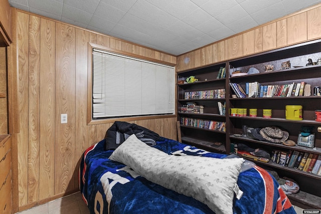 bedroom with light tile patterned floors and wood walls