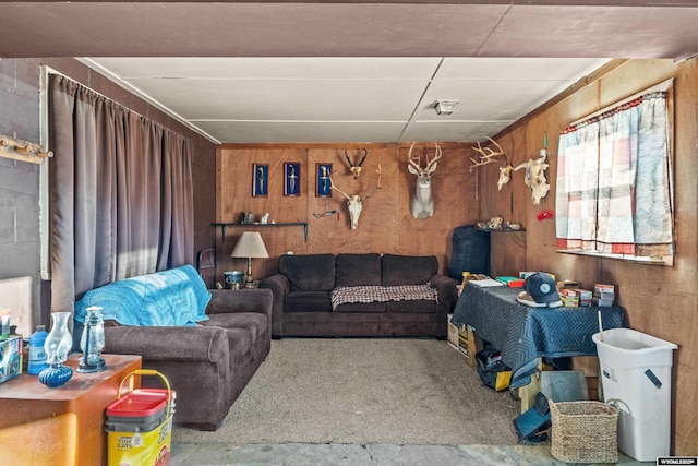 carpeted living room featuring wooden walls