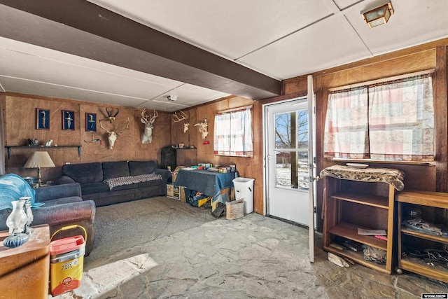 living room featuring beamed ceiling and wooden walls