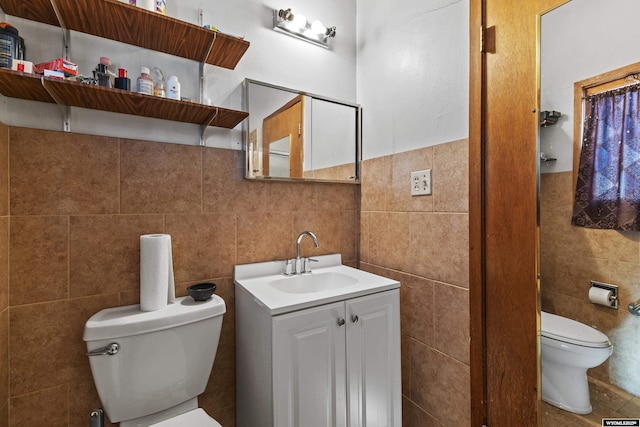 bathroom featuring vanity, toilet, and tile walls