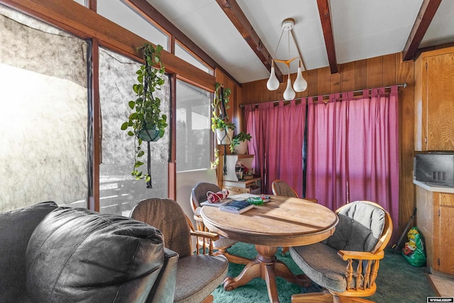 dining area featuring vaulted ceiling with beams and wooden walls