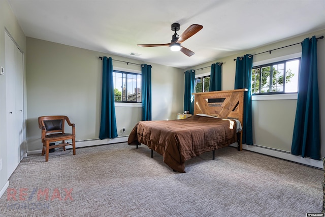 carpeted bedroom featuring multiple windows, a closet, ceiling fan, and a baseboard heating unit