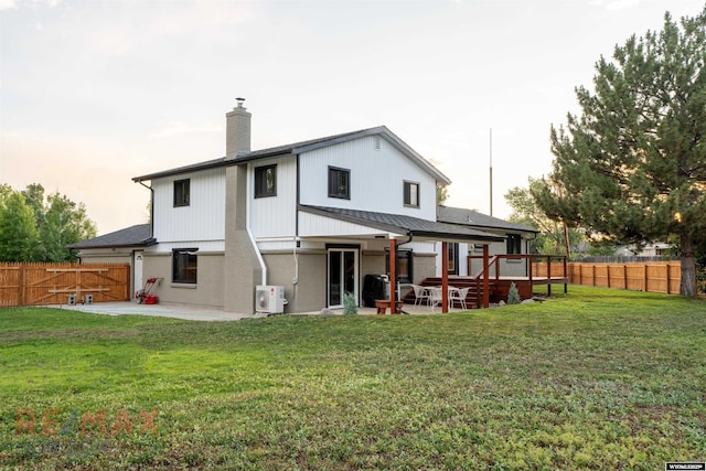 back house at dusk with a lawn, a patio area, and a deck