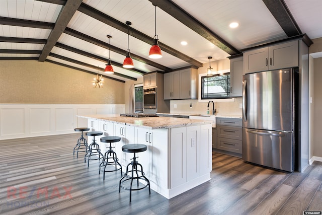 kitchen with gray cabinetry, a kitchen island, hanging light fixtures, and appliances with stainless steel finishes