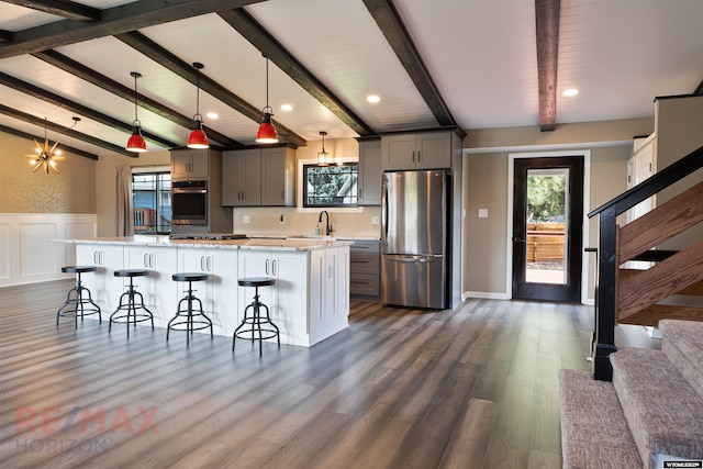 kitchen with a kitchen bar, appliances with stainless steel finishes, gray cabinetry, a center island, and hanging light fixtures