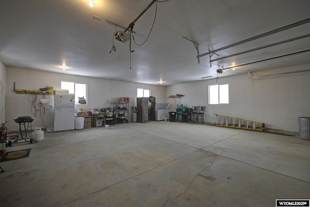 garage with a garage door opener and white fridge