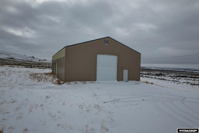 snow covered structure with a garage