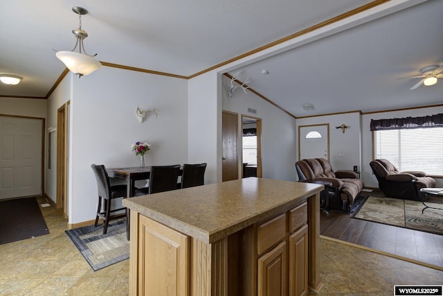 kitchen with pendant lighting, ceiling fan, ornamental molding, a kitchen island, and vaulted ceiling