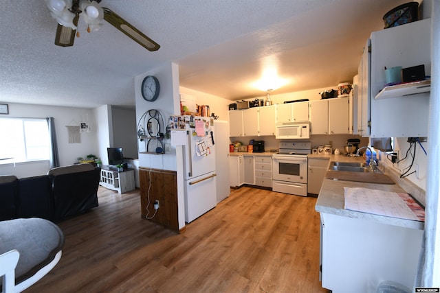 kitchen with white appliances, sink, hardwood / wood-style flooring, a textured ceiling, and white cabinetry