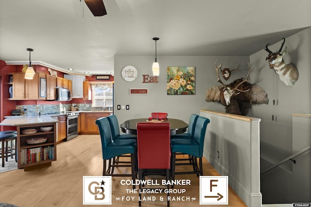 dining area with ceiling fan, light wood-type flooring, and sink