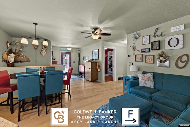 interior space featuring ceiling fan, a textured ceiling, and light hardwood / wood-style flooring