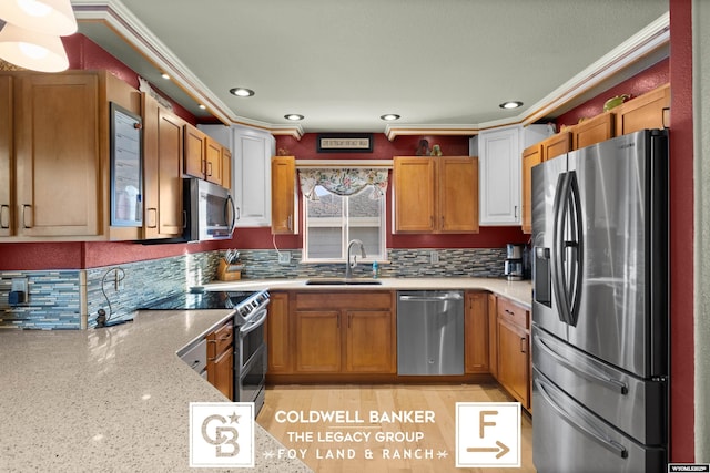 kitchen with stainless steel appliances, light stone counters, crown molding, and sink