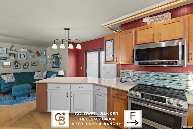 kitchen with pendant lighting, backsplash, light wood-type flooring, appliances with stainless steel finishes, and white cabinetry