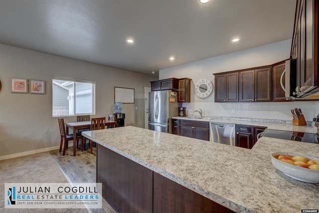 kitchen featuring sink, kitchen peninsula, decorative backsplash, dark brown cabinetry, and stainless steel appliances