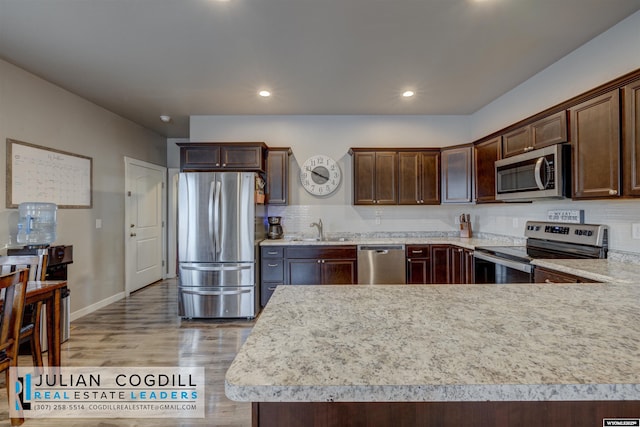 kitchen featuring light hardwood / wood-style floors, dark brown cabinetry, sink, and appliances with stainless steel finishes