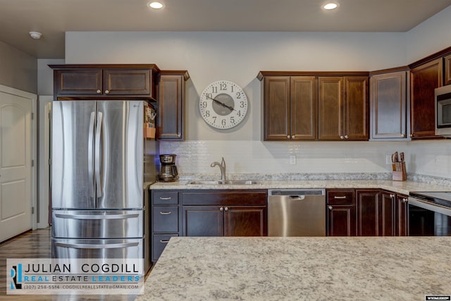 kitchen featuring decorative backsplash, stainless steel appliances, light stone counters, and sink