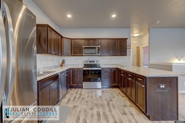 kitchen featuring sink, light hardwood / wood-style flooring, kitchen peninsula, dark brown cabinets, and appliances with stainless steel finishes