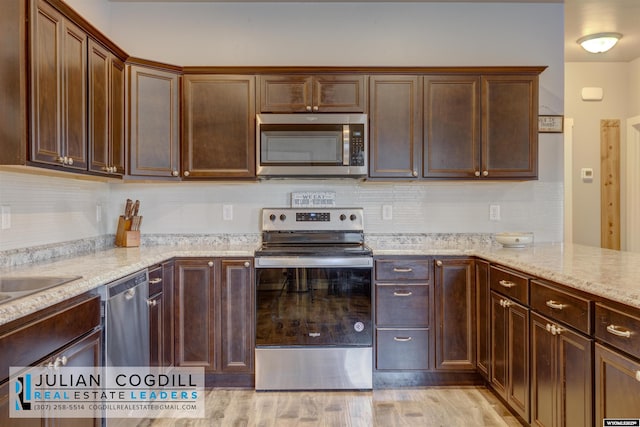 kitchen with appliances with stainless steel finishes, dark brown cabinetry, and light stone counters