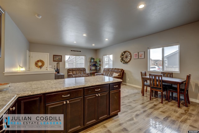 kitchen featuring plenty of natural light, light hardwood / wood-style floors, light stone countertops, and dark brown cabinetry