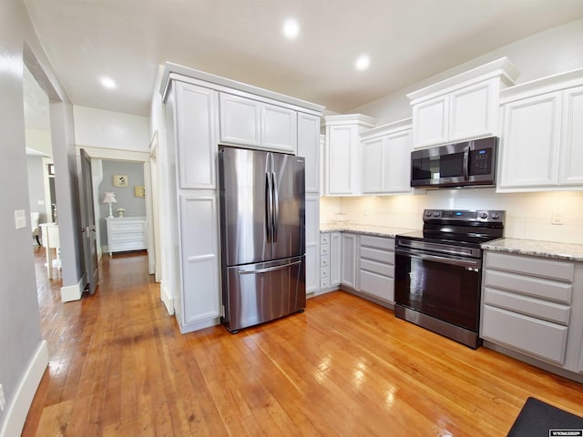 kitchen featuring decorative backsplash, stainless steel appliances, white cabinets, and light stone counters