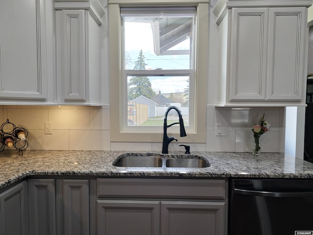 kitchen with gray cabinetry, dishwasher, sink, tasteful backsplash, and light stone counters