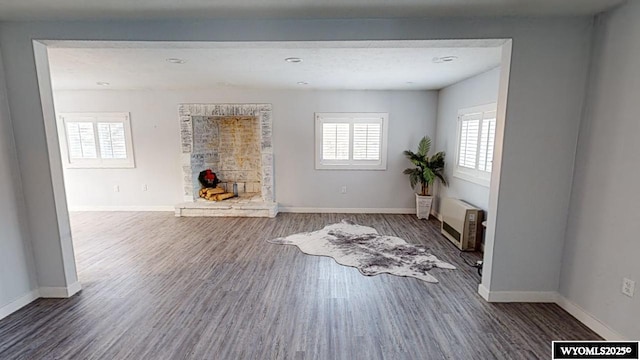 living room with a wall mounted air conditioner, hardwood / wood-style floors, heating unit, and a healthy amount of sunlight