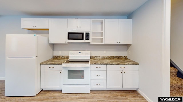 kitchen with white cabinetry, dark stone countertops, and white appliances