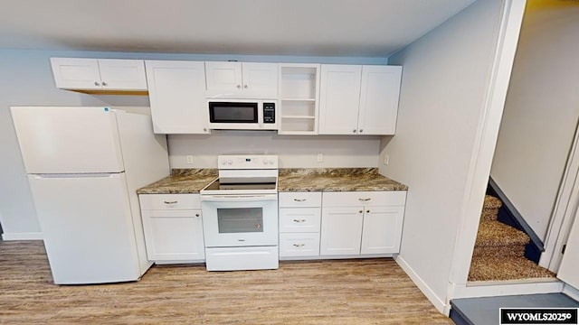 kitchen with light wood-type flooring, white appliances, white cabinetry, and dark stone counters