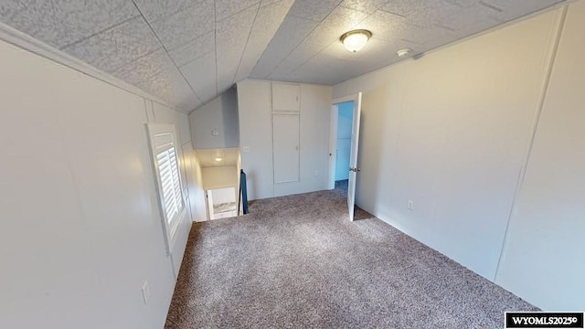 carpeted empty room with lofted ceiling