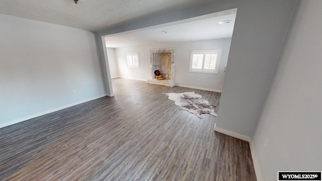 unfurnished living room featuring wood-type flooring, a fireplace, and a wealth of natural light