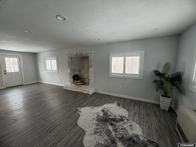 living room featuring a textured ceiling, plenty of natural light, dark hardwood / wood-style flooring, and a fireplace