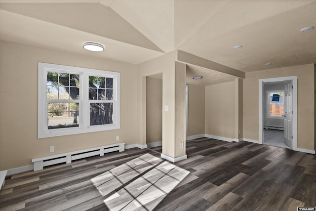 empty room featuring dark hardwood / wood-style flooring, a baseboard radiator, and vaulted ceiling