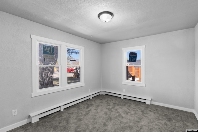 empty room with dark colored carpet, a textured ceiling, and a baseboard radiator