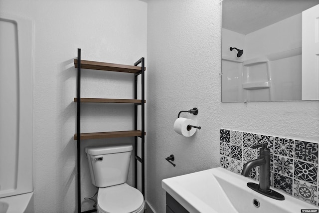 bathroom featuring vanity, toilet, and backsplash