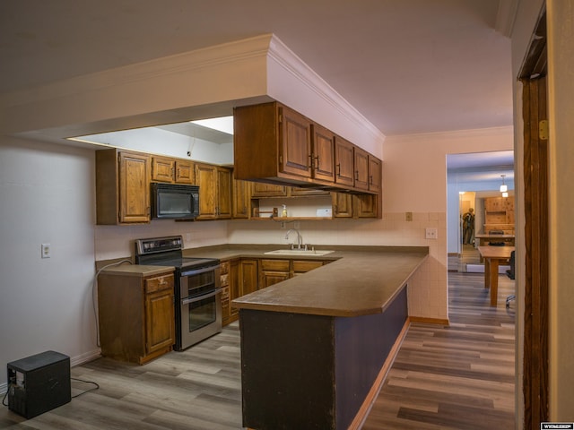 kitchen featuring double oven range, kitchen peninsula, ornamental molding, light hardwood / wood-style flooring, and sink